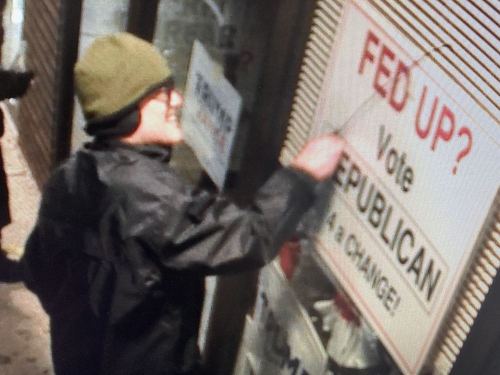 Surveillance still of an individual tampering with a ROWT campaign sign at night