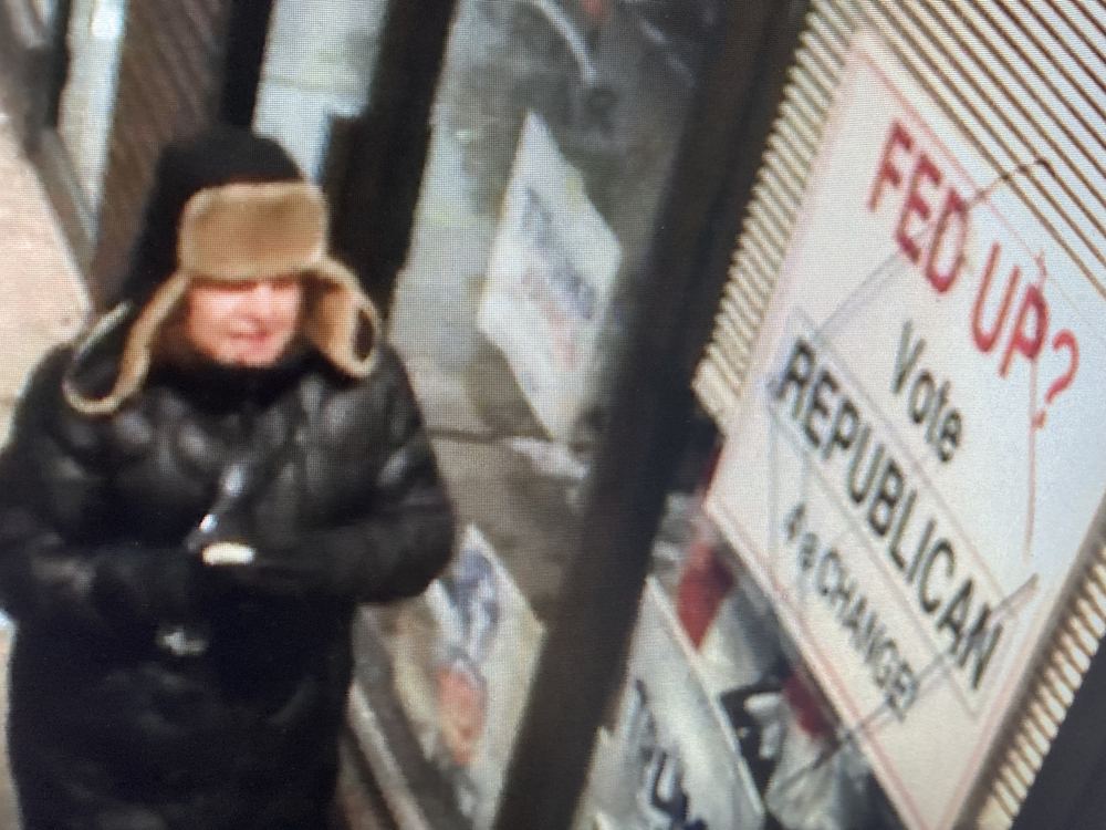 Surveillance still of an individual tampering with a ROWT campaign sign at night